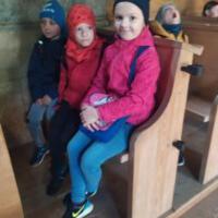 Na zdjęciu dzieci z wychowawcami wewnątrz kościoła/cerkwi. Niektóre dzieci klęczą przed krzyżem inne siedzą w ławce a jeszcze inne podziwiają ołtarz, malowidła, rzeźby.