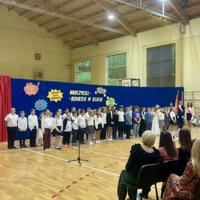 Grupa czwartoklasistów, którzy występowali w akademii stoi na tle dekoracji.