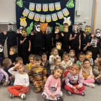 Dzieci świętują dzień zwierzaka, są ubrane na czarno a na twarzach mają maski różnych zwierząt.