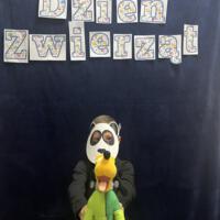 Dzieci świętują dzień zwierzaka, są ubrane na czarno a na twarzach mają maski różnych zwierząt.