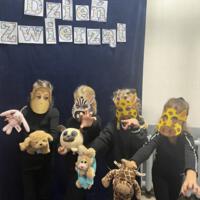 Dzieci świętują dzień zwierzaka, są ubrane na czarno a na twarzach mają maski różnych zwierząt.