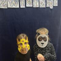 Dzieci świętują dzień zwierzaka, są ubrane na czarno a na twarzach mają maski różnych zwierząt.