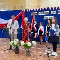 Pani dyrektor oraz wójt zabierają głos w uroczystości. W tle napis GMINNE ROZPOCZĘCIE ROKU SZKOLNEGO 2023-2024. Z boku stoją dwie dziewczynki ubrane galowo, które prowadziły część oficjalną akademii.