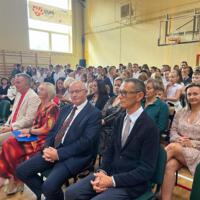 Na zdjęciach uczniowie szkoły, którzy oglądali akademię. Młodsze dzieci siedzą na ławeczkach. Starsze na krzesłach, najstarsi stoją z tyłu. Wszyscy są odświętnie ubrani.