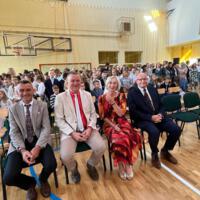 Na zdjęciach uczniowie szkoły, którzy oglądali akademię. Młodsze dzieci siedzą na ławeczkach. Starsze na krzesłach, najstarsi stoją z tyłu. Wszyscy są odświętnie ubrani.