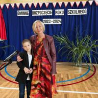 Dyrektor szkoły z uczniem klasy trzeciej który recytował wiersz podczas akademii. W tle dekoracja z sali gimnastycznej.