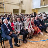 Na zdjęciach uczniowie szkoły, którzy oglądali akademię. Młodsze dzieci siedzą na ławeczkach. Starsze na krzesłach, najstarsi stoją z tyłu. Wszyscy są odświętnie ubrani.