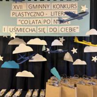Na zdjęciu prezentacja prac oraz nagród dla uczestników konkursu. Na granatowym tle rozwieszona dekoracja w postaci chmur.
