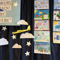 Na zdjęciu prezentacja prac oraz nagród dla uczestników konkursu. Na granatowym tle rozwieszona dekoracja w postaci chmur.