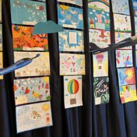 Na zdjęciu prezentacja prac oraz nagród dla uczestników konkursu. Na granatowym tle rozwieszona dekoracja w postaci chmur.